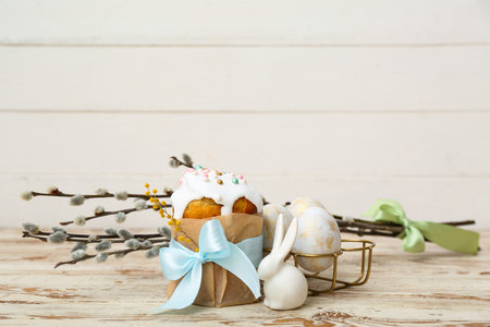 Tasty Easter cake with eggs, toy bunny and willow branches on white wooden table