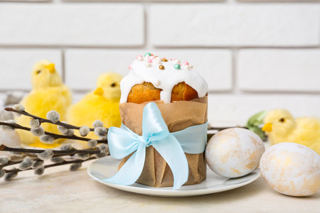 Plate with tasty Easter cake, eggs, chicks and willow branches on white tableの写真素材