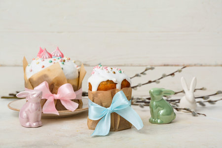 Tasty Easter cakes with toys bunnies and willow branches on white table