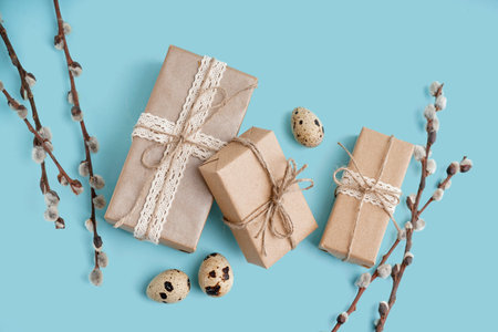 Easter gift boxes with eggs and branches of pussy willow on blue background