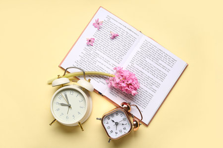 Different alarm clocks with book and hyacinth flowers on beige backgroundの写真素材