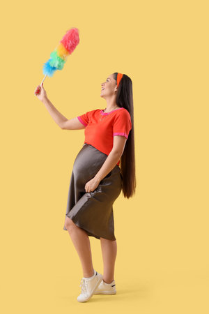 Young pregnant woman with pp-duster on yellow backgroundの写真素材