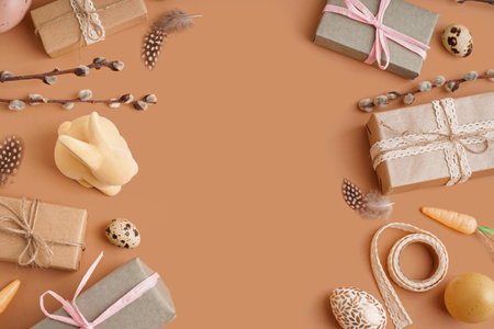 Frame made of gift boxes with Easter toy bunny and feathers on brown backgroundの写真素材