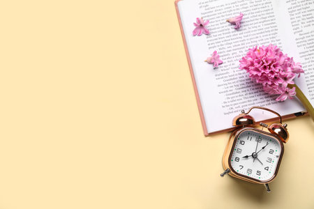 Alarm clock with book and hyacinth flowers on beige backgroundの写真素材