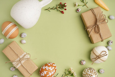 Beautiful wreath made of Easter eggs, flowers and gift boxes on green background
