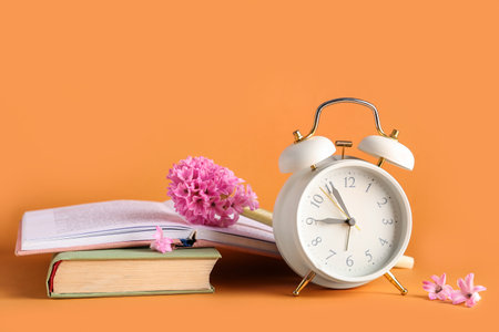 Alarm clock with books and hyacinth flowers on orange backgroundの写真素材