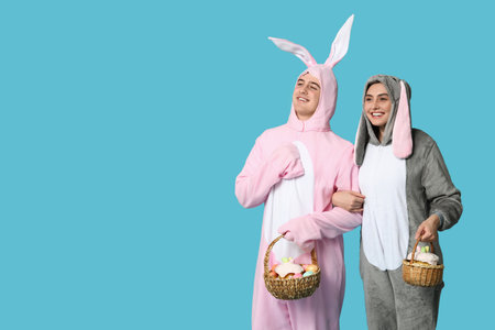 Beautiful young couple in bunny costume with Easter baskets on blue backgroundの写真素材