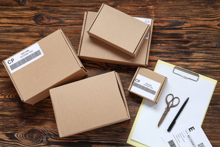 Cardboard packages with labels and clipboard on wooden table