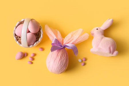 Ceramic basket with toy bunny and Easter eggs on yellow backgroundの写真素材
