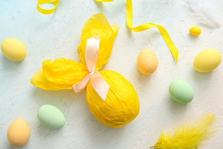 Painted and chocolate Easter eggs wrapped in paper on blue grunge background