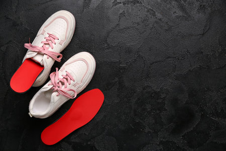 Sneakers and red orthopedic insoles on black grunge backgroundの写真素材