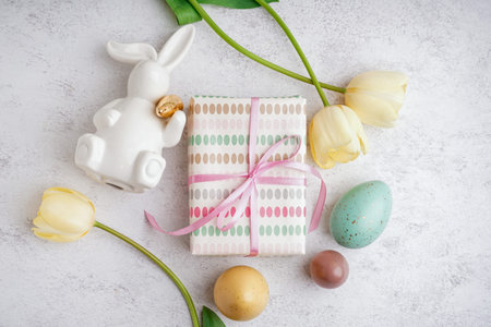 Painted Easter eggs with gift box, tulip flowers and bunny on white grunge background
