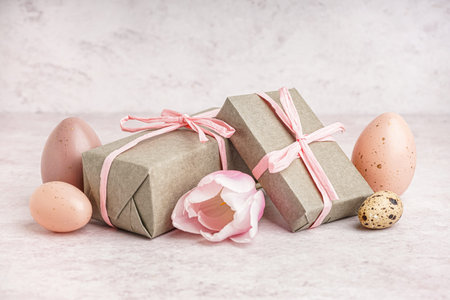 Painted Easter eggs with gift boxes and tulip flower on beige grunge background