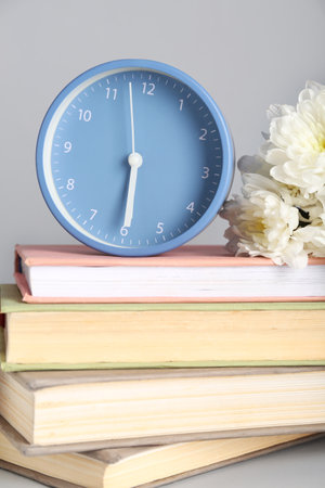 Alarm clock with books and chrysanthemum flowers on gray backgroundの写真素材