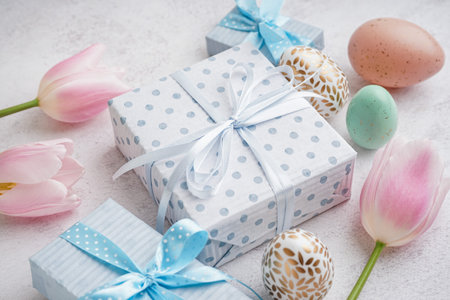 Painted Easter eggs with gift boxes and tulip flowers on white grunge backgroundの写真素材