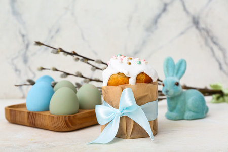 Tasty Easter cake with eggs, willow branches and toy bunny on white background