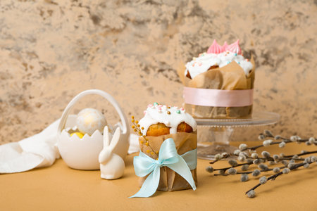 Tasty Easter cakes with eggs, toy bunny and willow branches on brown table