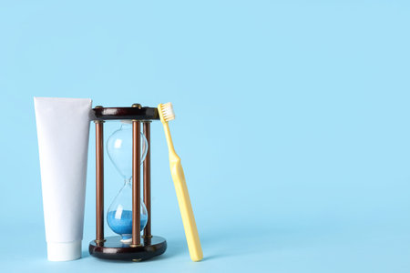 Hourglass, toothpaste and toothbrush on blue background