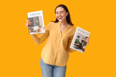 Beautiful woman with interior magazines on yellow backgroundの写真素材