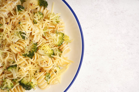 Delicious fusilli pasta with broccoli and cheese in bowl on light background, closeupの写真素材