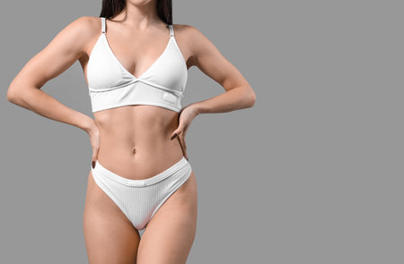Young woman in white underwear on gray backgroundの写真素材