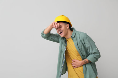 Portrait of happy male engineer laughing on gray background
