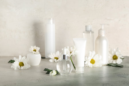 Different cosmetic products and chamomile flowers on table against light backgroundの写真素材