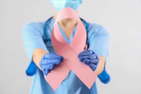 Female doctor with pink ribbon on light background, closeup. Breast cancer awareness conceptの写真素材