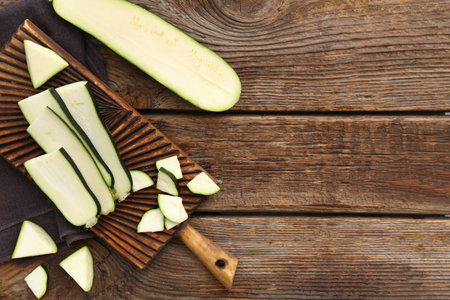 Board with slices of fresh green zucchini on wooden backgroundの写真素材
