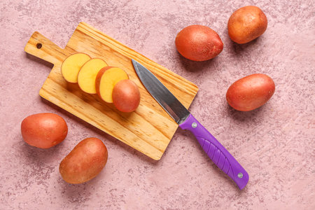 Wooden board with slices of fresh raw potato on pink backgroundの写真素材