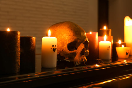 Burning candles and skull for Halloween celebration on grand piano in dark room, closeupの写真素材