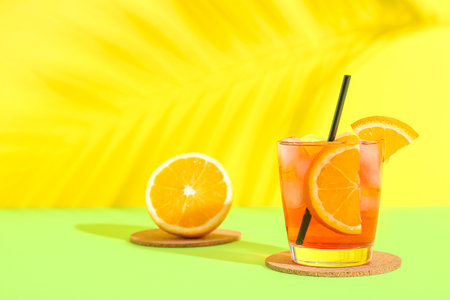 Glass of tasty Negroni cocktail and palm leaf shadow on color backgroundの写真素材
