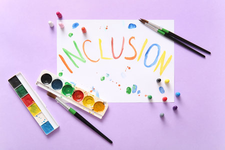 Paper with word INCLUSION, paints, brushes and pawns on lilac background