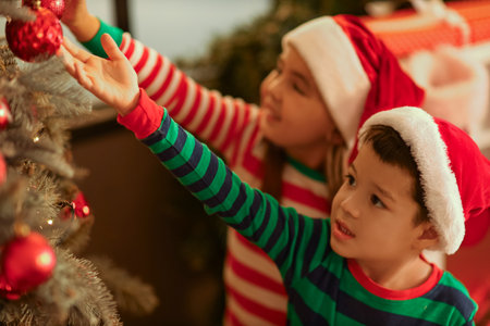 Cute little children in Santa hats near Christmas tree at home, closeupの写真素材