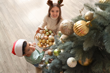 Cute little children decorating Christmas tree at homeの写真素材