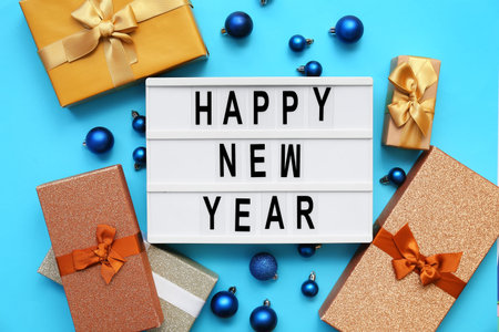 Text HAPPY NEW YEAR with Christmas balls and gift boxes on blue background