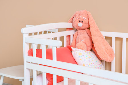 Crib with toy bunny near beige wallの写真素材