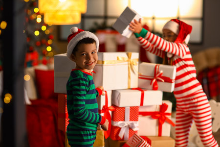 Cute little children in Santa hats with presents at home on Christmas Eveの写真素材