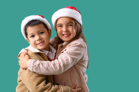 Cute little children in Santa hats hugging on green backgroundの写真素材