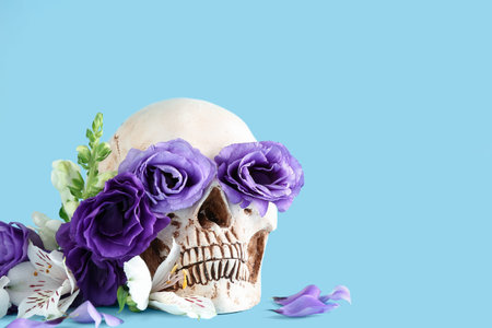 Human skull with beautiful flowers on blue backgroundの写真素材
