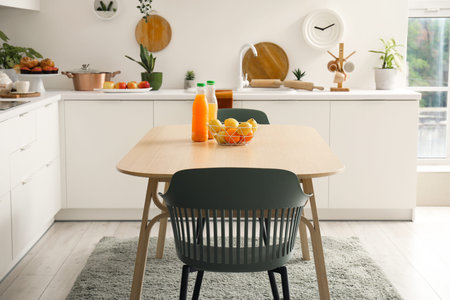 Wooden dining table with orange juice and fresh fruits in modern kitchen