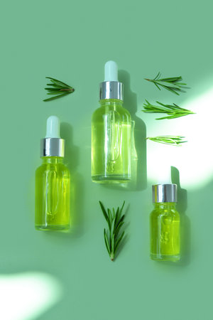 Bottles of healthy essential oil with herbs on green backgroundの写真素材