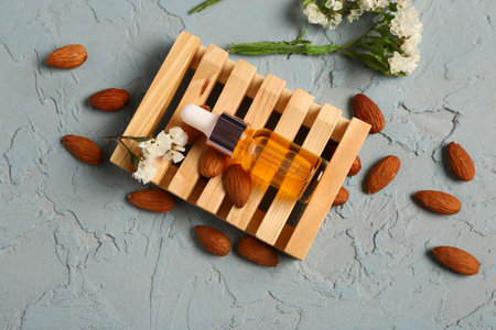 Bottles of cosmetic oil with beautiful flowers and almond on blue backgroundの写真素材