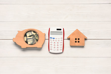 Calculator, money, wooden house and piggy bank on light wooden background. Mortgage conceptの写真素材