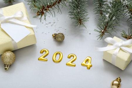 Figure 2024 with Christmas tree branches and gift boxes on blue background