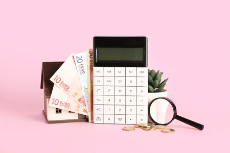 Calculator, house model, money, magnifier and houseplant on pink background. Mortgage conceptの写真素材