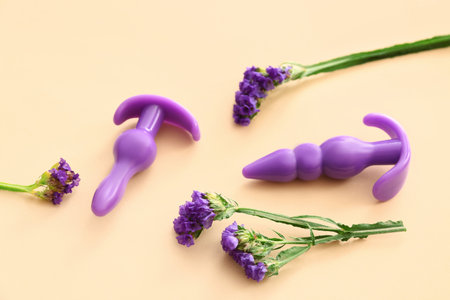 Purple anal plugs from sex shop and beautiful lavender flowers on beige background, closeupの写真素材