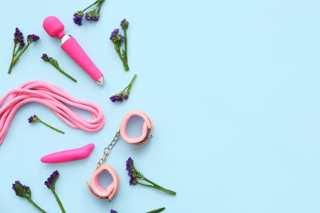 Sex toys and beautiful flowers on blue background
