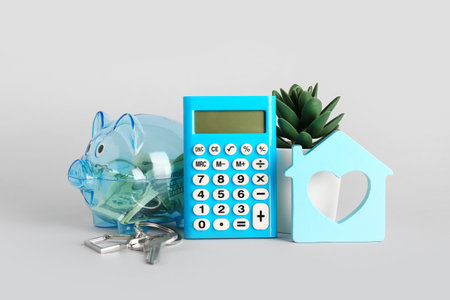Calculator, house model, keys, piggy bank, money and houseplant on light background. Mortgage conceptの写真素材