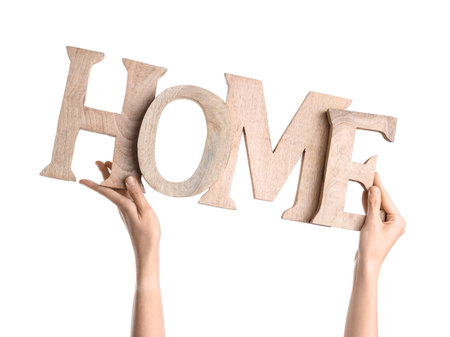 Female hands holding decorative word HOME on white backgroundの写真素材
